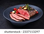 Small photo of Modern style traditional Commonwealth Sunday roast with sliced cold cuts roast beef with tomatoes and scallions as top view in a design plate