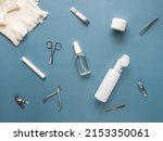 Small photo of Top view of face and nail care set: towel, washing gel,nail file, nippers, scissors, tweezers, body oil, face and hand cream, tweezers, eyebrow oil. Spa and skin care concept. Blue background.Flat lay