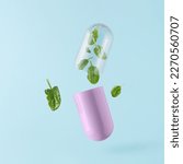Small photo of Pink pill with leafy green vegetable spinach floating above isolated pastel blue background. Minimal abstract agricultural concept. Natural food. Vitamins K, A, C, folate and antioxidants flavonoids.