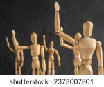 Small photo of wooden mannequins as obedient subservient people on dark background