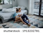 Happy couple at home, man and woman surfing the Internet, happy couple making a video call from home, young couple with a laptop, spending time together at home, young couple in pyjamas with a laptop