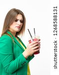 Small photo of Healthy Food Eating. Choosy Thinking Woman With Both Green and Red Detox Vegetable Smoothie. Posing in Green Jacket Over White.Unpleased Facial Expression.Vertical Image