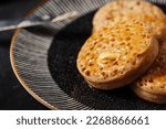 Small photo of Toasted english crumpet with butter on a black plate