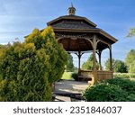 A wooden gazebo with a cement base and an ornate roof.