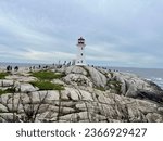 Small photo of Peggy's Cove, NS, CAN, 8.15.23 - Tourists climbing on the rocks around Peggy's Cove lighthouse.