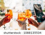 Girls holding alcoholic drinks and taking photo on her smartphone