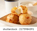 Minas Gerais cheese bread, hot, with a cup of black coffee and cream cheese, on a white tablecloth, copy space