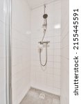 Small photo of Shower faucets attached to tiled wall near glass partition and ornamental curtail in washroom at home