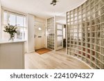 Small photo of a glass block wall in a hallway with wooden flooring and white trim on the walls there is a vase full of flowers