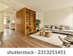 Small photo of a living room with wood flooring and white rugs on the floor, there is an open bookcase