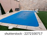 Small pool covered with a blue tarpaulin during the winter season to cover it and prevent dirt and objects from entering the water.