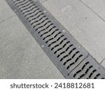 Small photo of Drainage element, storm drainage on a paved area or road. The system channel (tray) is covered with a metal grate.