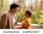 Happy grandmother and grandson enjoy time together. Positive middle age woman playing with little, cute grandchild, laughing, having fun. 50-year-old grandma with grandkid. Multi-generational family.