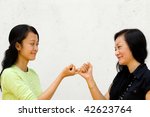 Small photo of two asian female teenager make peace to each other after the fights. bury the hatchet