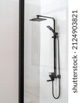 Small photo of Closeup of black shower faucet in bathroom with transparent partition. Water flowing. Contemporary shower zone with rain head. Luxury house for sale