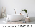 Small photo of White modern tub in minimalistics bathroom interior. Porcelain bathtub with classic design in comfortable apartment or hotel room. Home decor and houseplant in spa centre