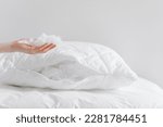 cropped shot of female hand holding and showing fluffy fiberfill from pillow on white background with copy space, hypoallergenic stuffing, comfort sleeping concept