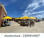 Small photo of New York, NY USA - May 28, 2023 - People sitting at the picnic tables in front of the concession stands at Riis Beach Cooperative at Jacob Riis Park on the Rockaway Peninsula in Queens, New York City