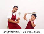 Small photo of The joy of a father and son wearing kitchen apron while holding kitchen ware. Isolated on white