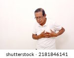 Elderly asian man standing while holds his chest, suffering from chest pain. Isolated on white