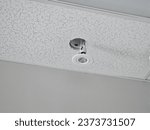 A broken light hanging from a hole in a ceiling with the wires exposed.