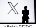 Small photo of CALIFORNIA, USA, 24. JULY 2023: New logo of Twitter. Silhouette of Elon Musk in front of black banner with Twitter new X logo in background.