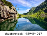 Young couple jump together into lake in mountains with beautiful blue water and reflexion. 
