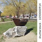 Small photo of Slavyansk-on-Kuban, Russia - March 19, 2018: Wooden boat with masts for sails. The model of the ship in front of the lake in the city of Slavic-on-Kuban. An uneventful author, a public monument.