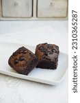 Small photo of A chocolate brownie, or simply a brownie, is a chocolate baked confection. Brownies come in a variety of forms and may be either fudgy or cakey, depending on their density.