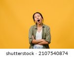 Portrait of Young Asia lady with negative expression, bored yawning tired covering mouth with hand in casual clothing isolated on yellow background with blank copy space. Facial expression concept