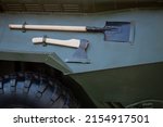 Small photo of A sapper shovel and an axe on a tank. The black wheel. Military equipment
