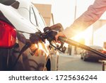 Man handle pumping gasoline fuel nozzle to refuel at petrol station. Transportation and ownership concept. Sunset lighting