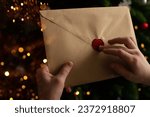 A child holds in his hands an envelope with wishes from Santa Claus. Wish list for Santa Claus inside 