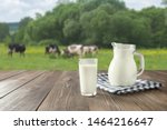 Fresh milk in glass on dark wooden tabletop and blurred landscape with cow on meadow. Healthy eating. Rustic style. Space for design.
