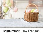 Basket with colorful pastel eggs on kitchen wooden tabletop. Spring easter composition. Space for text or design.
