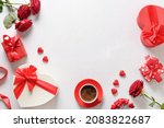 Valentine's day frame with love gifts, coffee, bouquet of red roses on white background. Romantic greeting card for dating. View from above. Copy space.