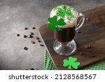 Patrick's Day and celebration with Irish coffee in glass cup with green sprinkles on gray background. Close up. Copy space.
