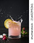 Pink gin cocktail garnish lemon and rose flowers on black background. Close up. Splash freshness rose beverage or lemonade.