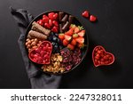 Valentines Day charcuterie board with chocolate, different sweets, berries and candies on black background. View from above.