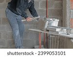Small photo of The builder is chiselling bricks with a chisel.