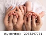 Small photo of Feet of newborn twins. Two pairs of baby feet. Parents, father mother hold newborn twins by the legs. Close up - toes, heels and feet of a newborn. Newborn brothers, sisters.