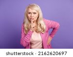 Small photo of Photo of aged senior lady finger cover lisp shh keep secret information isolated over purple color background