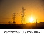 high voltage towers in the desert with sunset