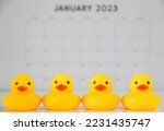 Small photo of Four yellow rubber ducks in a row, in the background January 2023 calendar is out of focus. Organisation concept, work, idiom, phrases, get your ducks in a row