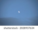 A half moon shines in early evening