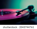 Vinyl DJ turntable in club lighting. close-up. pink tint