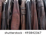 Collection of leather jackets on hangers in the shop. Many new men's leather winter jackets. Background and closeup texture of biker's leather, motorcycle jackets.