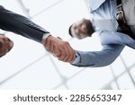 Business partners shaking hands in meeting hall bottom view