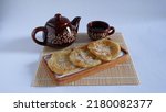 Small photo of Homemade Roti Canai or parata or kerala porotta, malabari parotta. Paratha with a sprinkling of sugar on wooden plate and bamboo base with a cup of tea on white grey background. Roti Maryam.