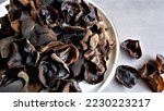 Small photo of Muer Mushroom on white ceramic plate on grey background. Edible dark fungus - auricularia polytricha, also known as cloud ear, black mushroom, jelly fungus, Jew's ear mushroom. Defocused. Soft Blurry.